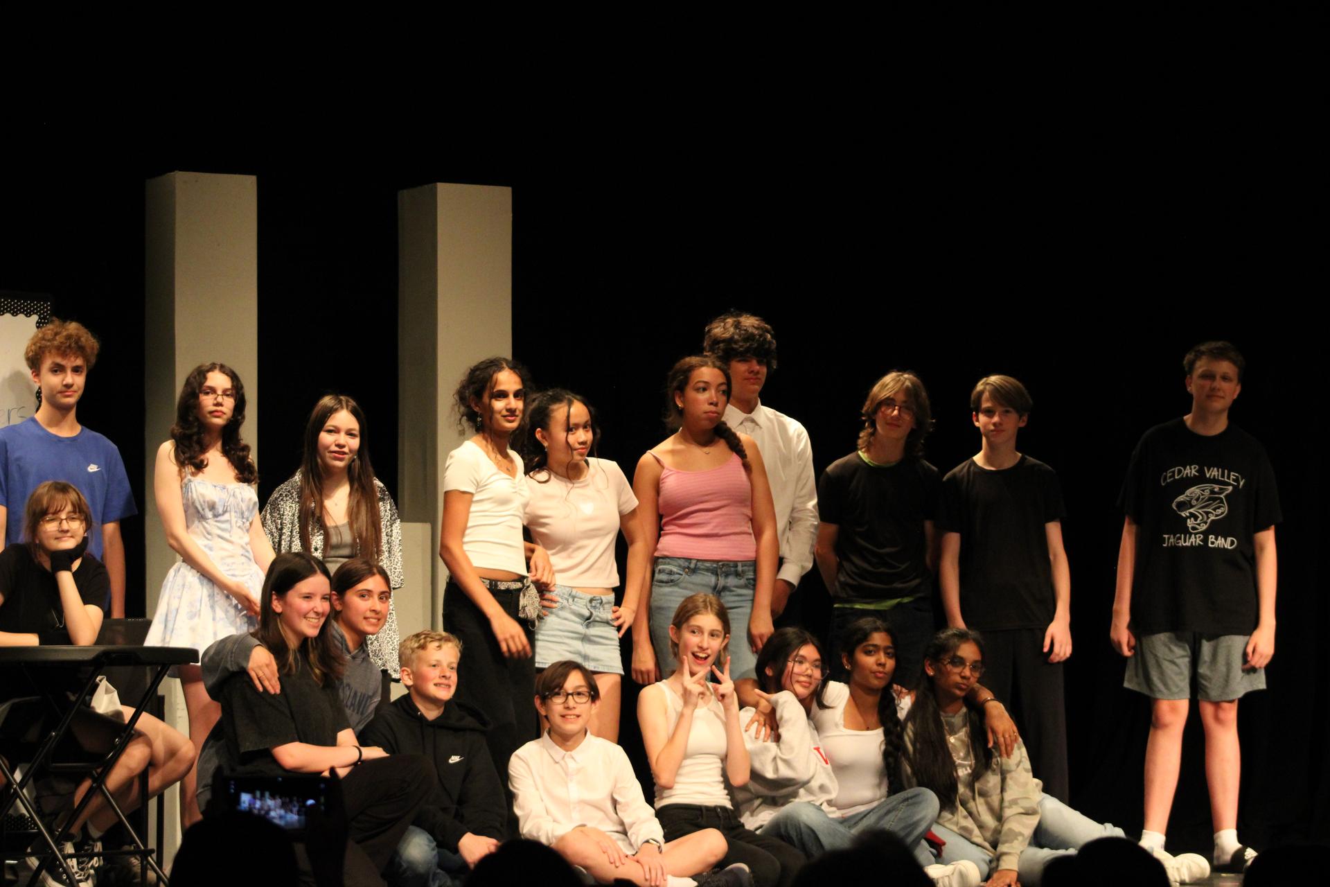 A group portrait of middle school theater students posing together on a stage following a performance.