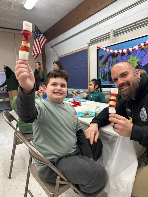 A father and son show off their marshmallow and strawberry creations at a family night event