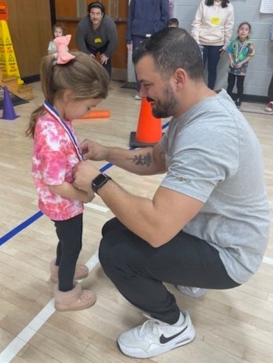A father helping his daughter put on a medal