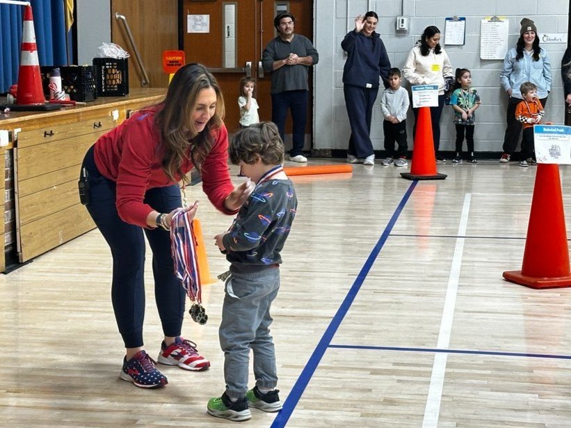 Principal Okuniewicz giving a medal to a student in the All Purpose Room