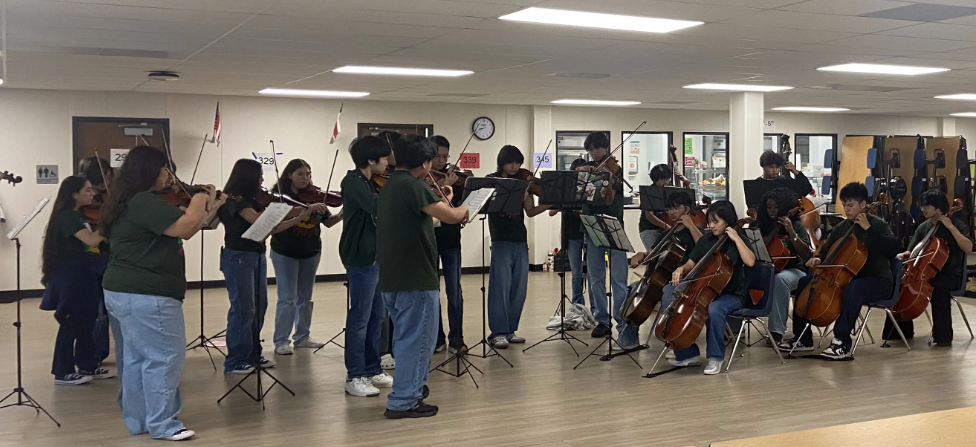 Students in green shirts with string instruments