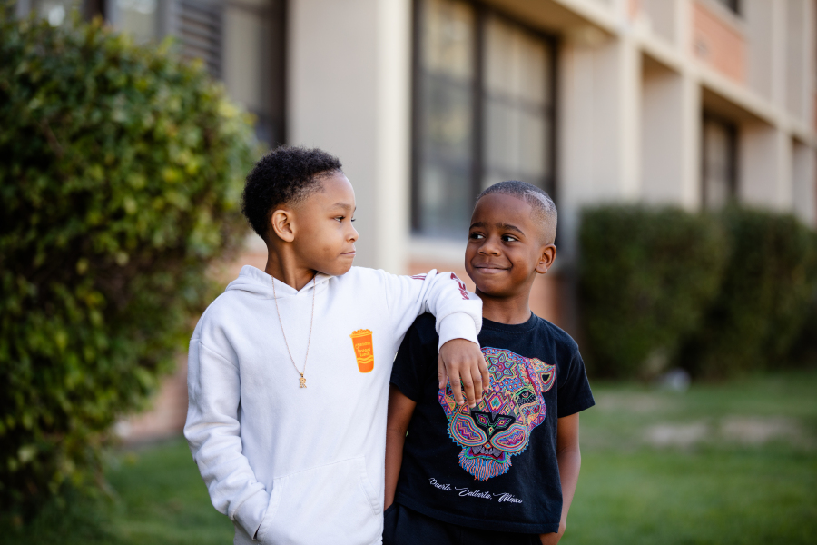 Two students stand in front of Hallett smiling at each other.