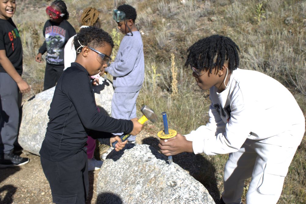 Students hammer into a rock at Balart
