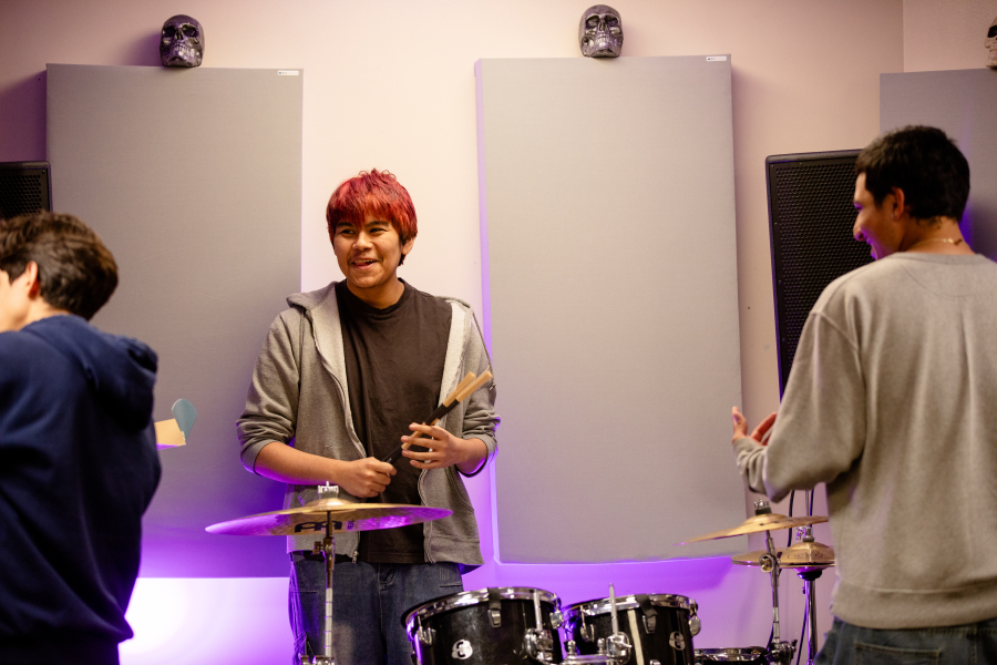 NEC Student plays on drums while smiling