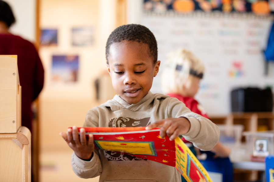 Hallett student smiles while reading a book