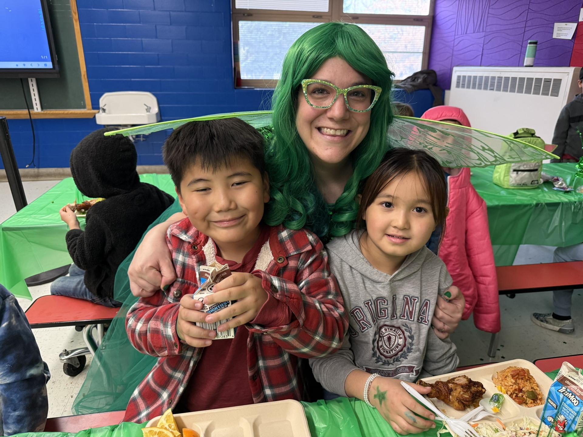 McMeen students smile and pose with teacher dressed up as a green fairy