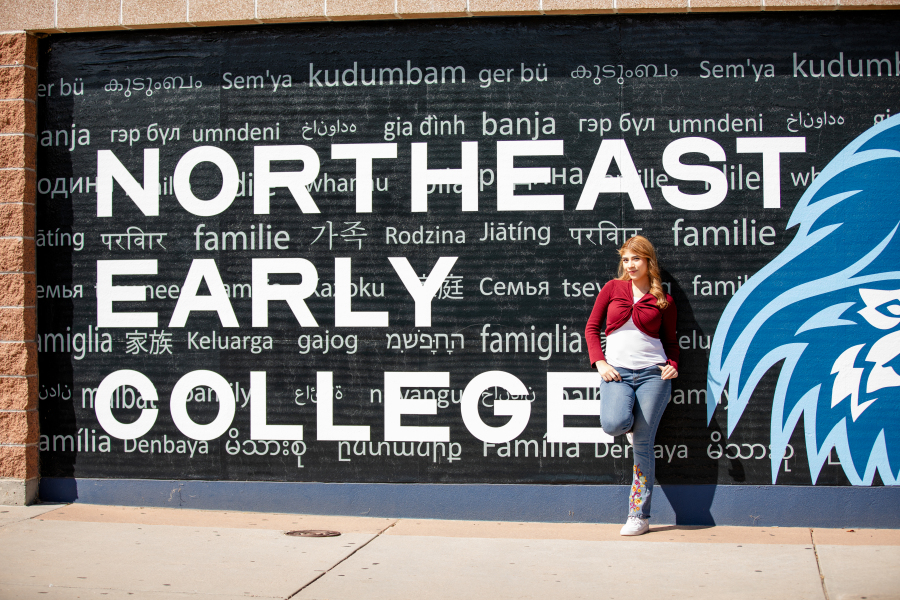 NEC Student smiling and leaning against NEC mural
