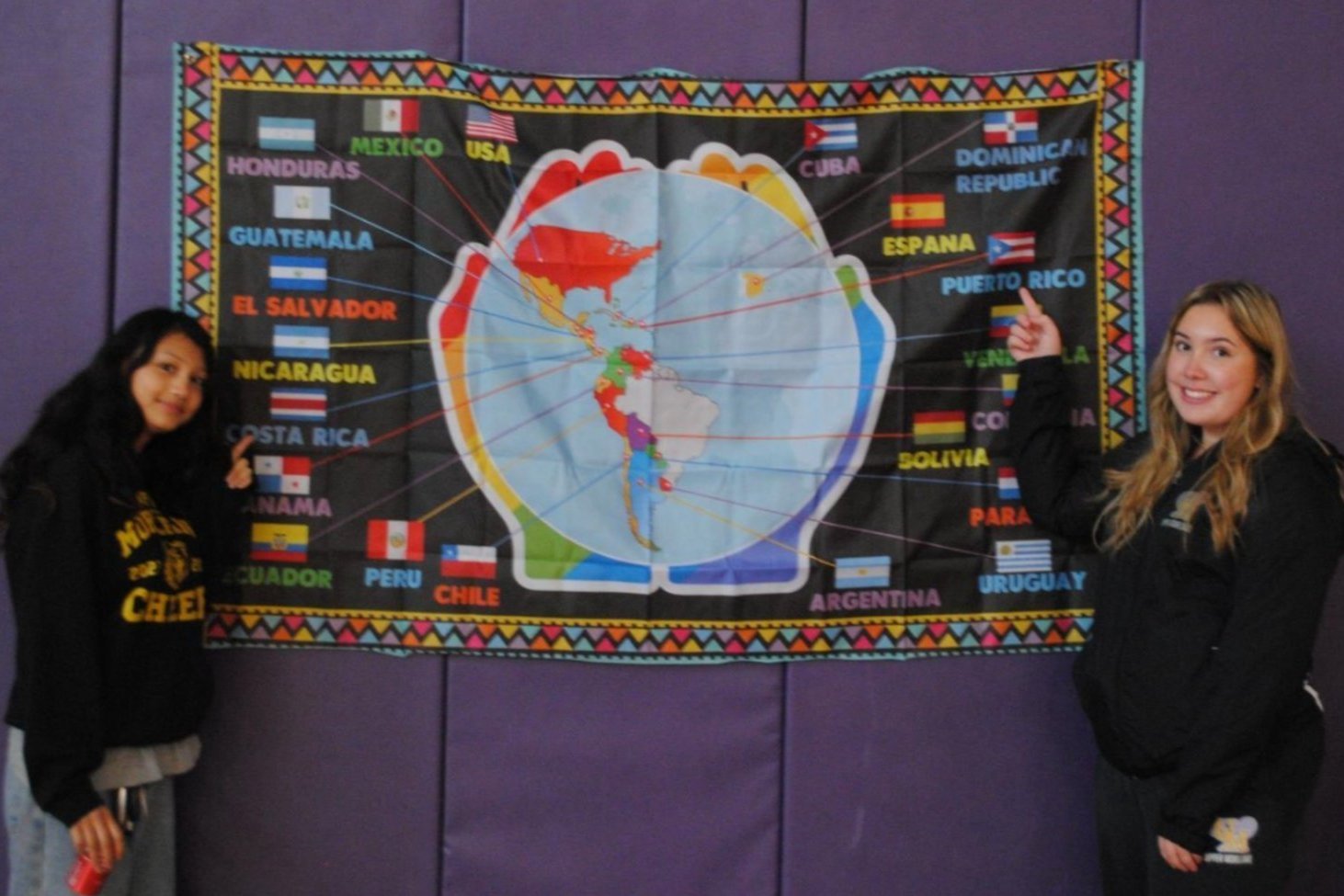Two students standing on either side of a world map.