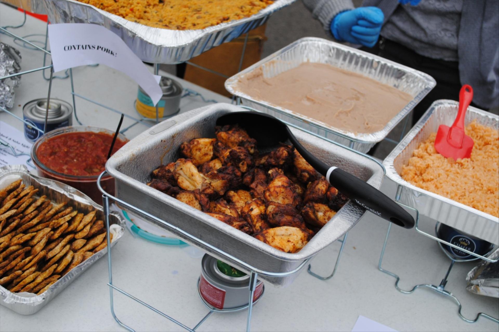 Food in warming plates displayed on a table.