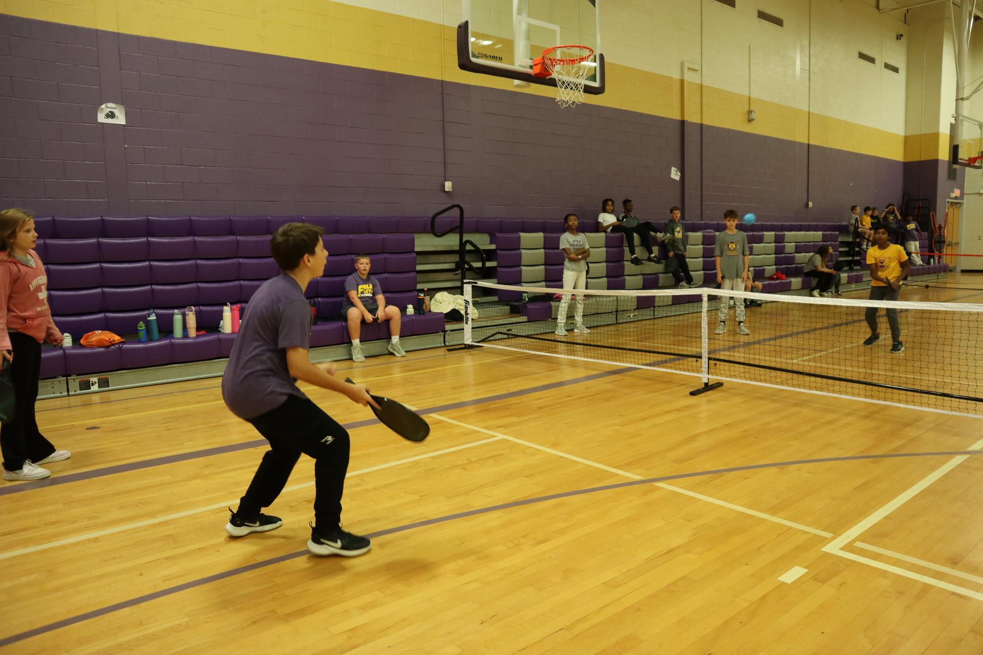 Students playing pickleball in an gymnasium.