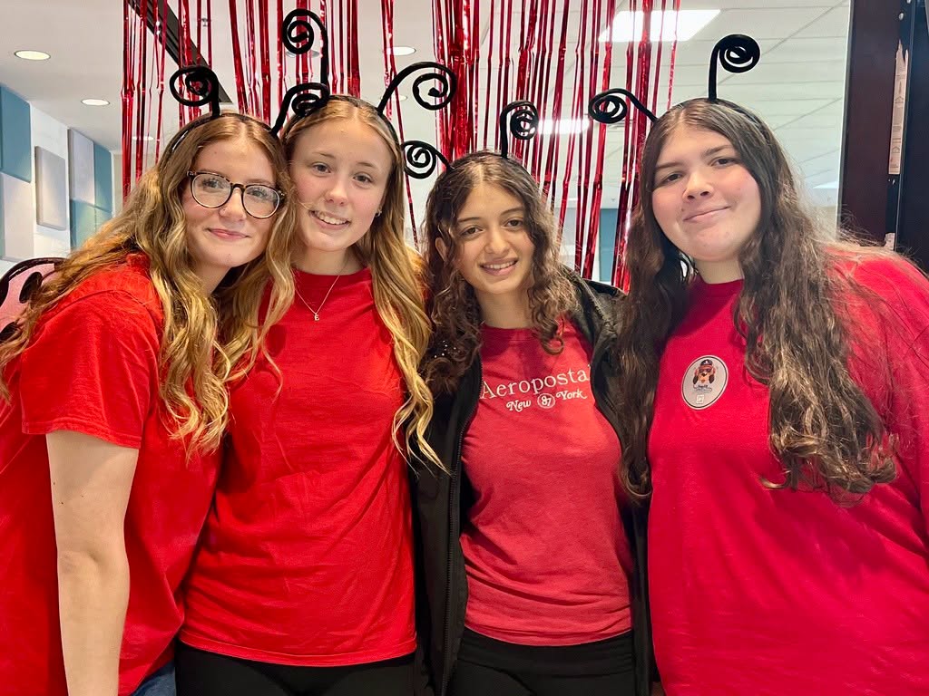 Four females wearing red shirts and black antennae headbands