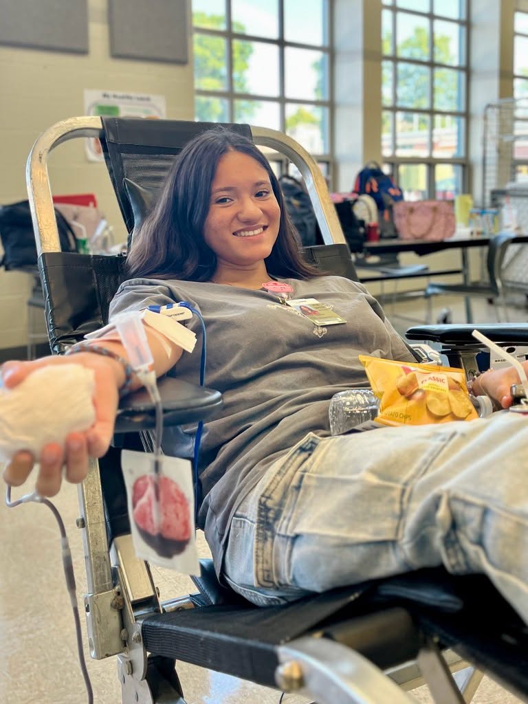Female sitting on a lounge chair with a snack in her lap donating blood