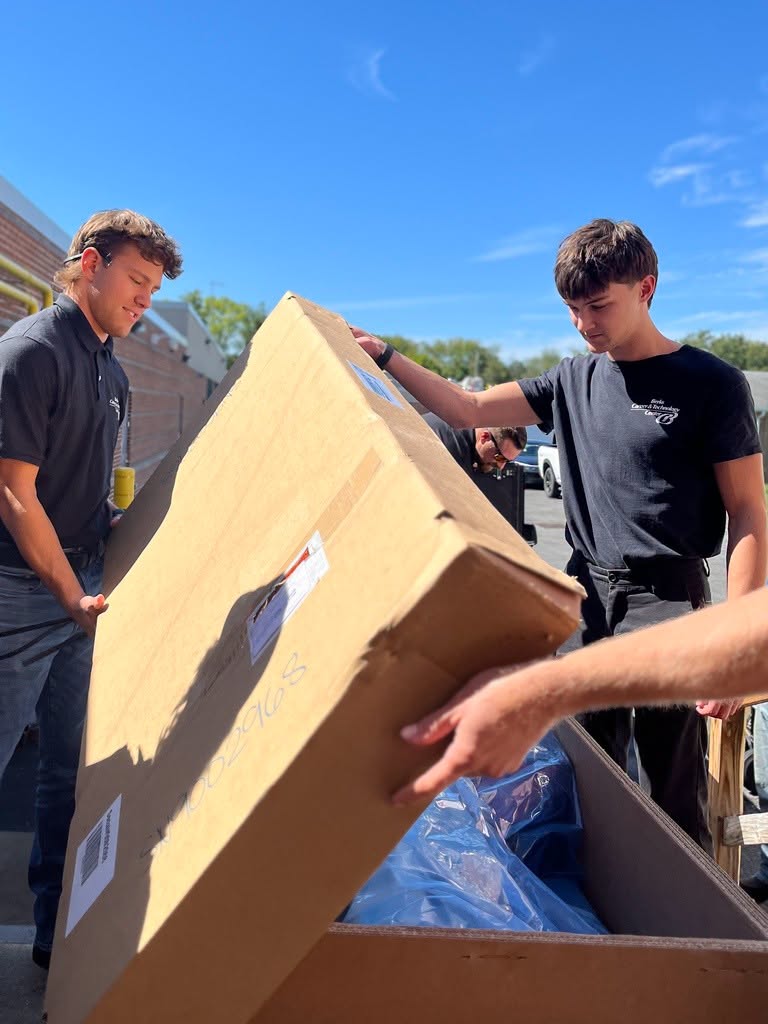 2 male students opening a large box