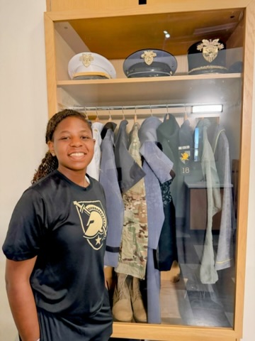 Jael Haynes-Lee stands next to a military uniform locker display.