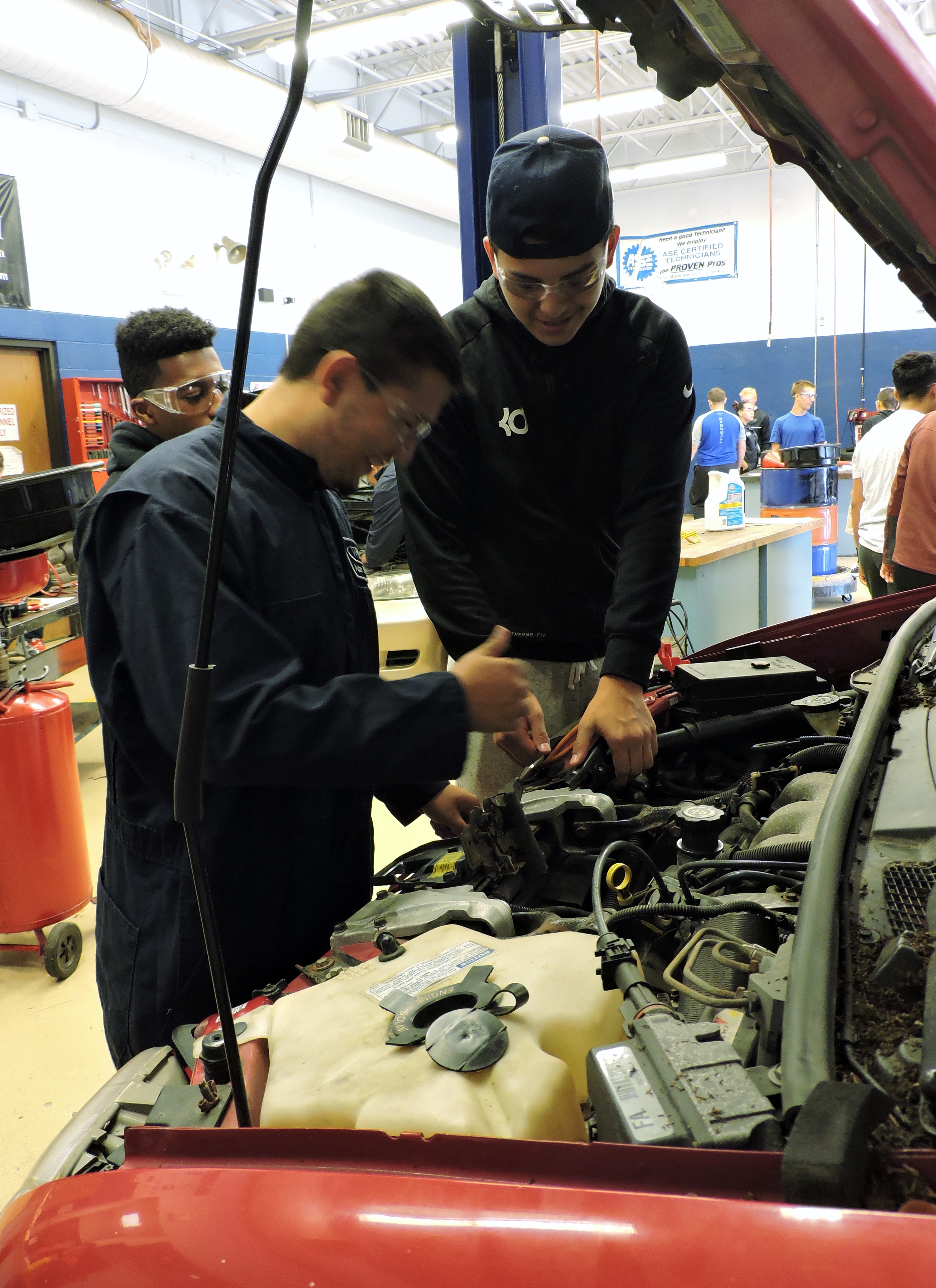 two students working on car