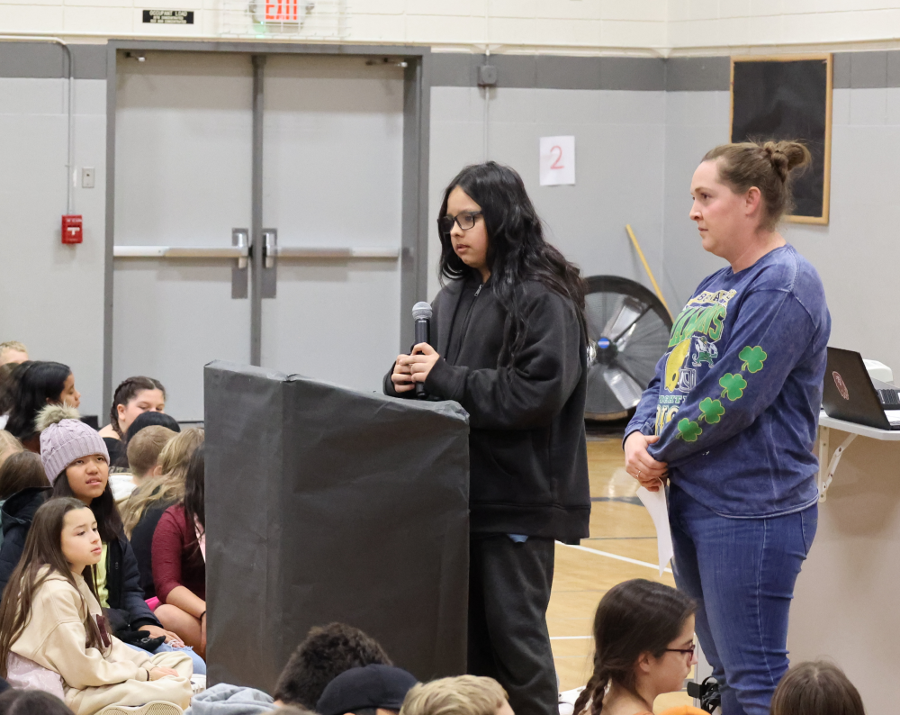 Kvli Raven spells a word as assistant principal Kelsey Kai and several students look on