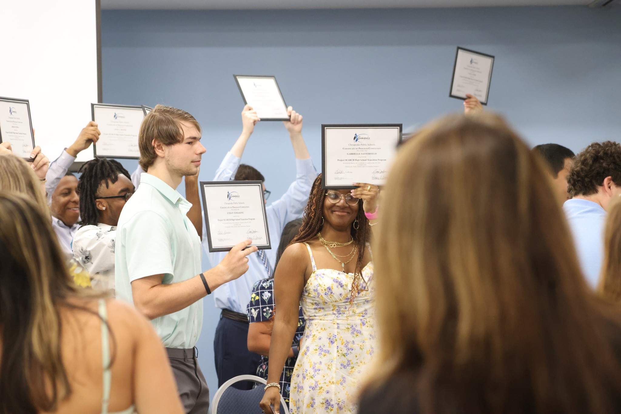 Students graduating from Project Search holding up their certificates.