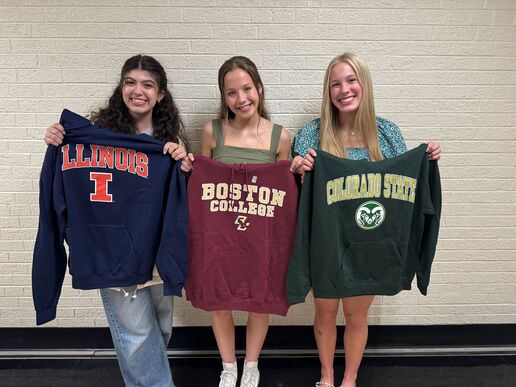 photo of 3 senior high school aged girls holding up sweatshirts that say the college they want to attend