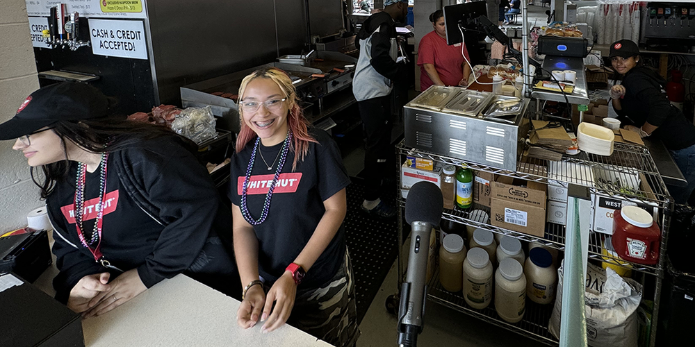 Dean students in White Hut shirts work at the counter