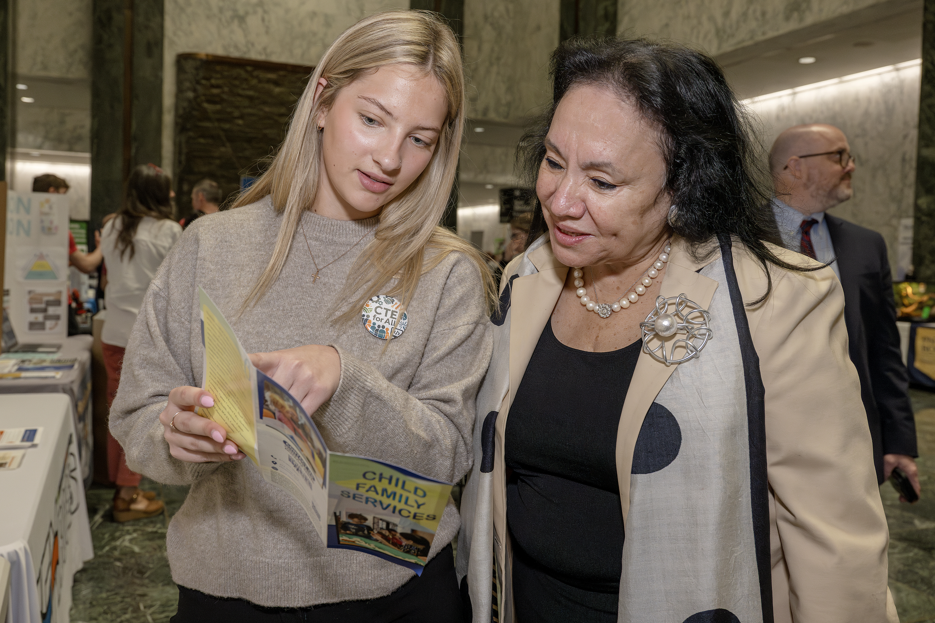 Student and education commissioner look at pamphlet