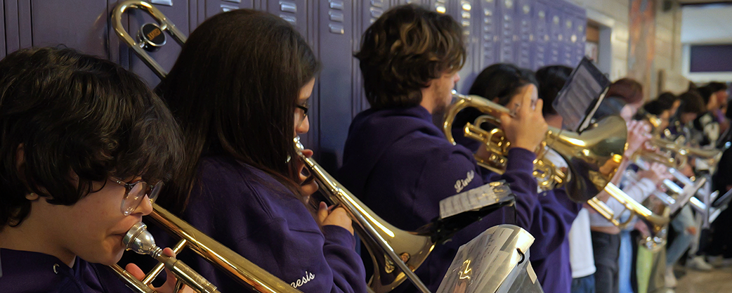 Student musicians playing instruments in front of hall lockers