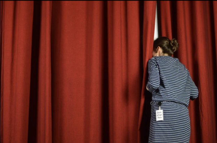 woman peeking behind red curtain