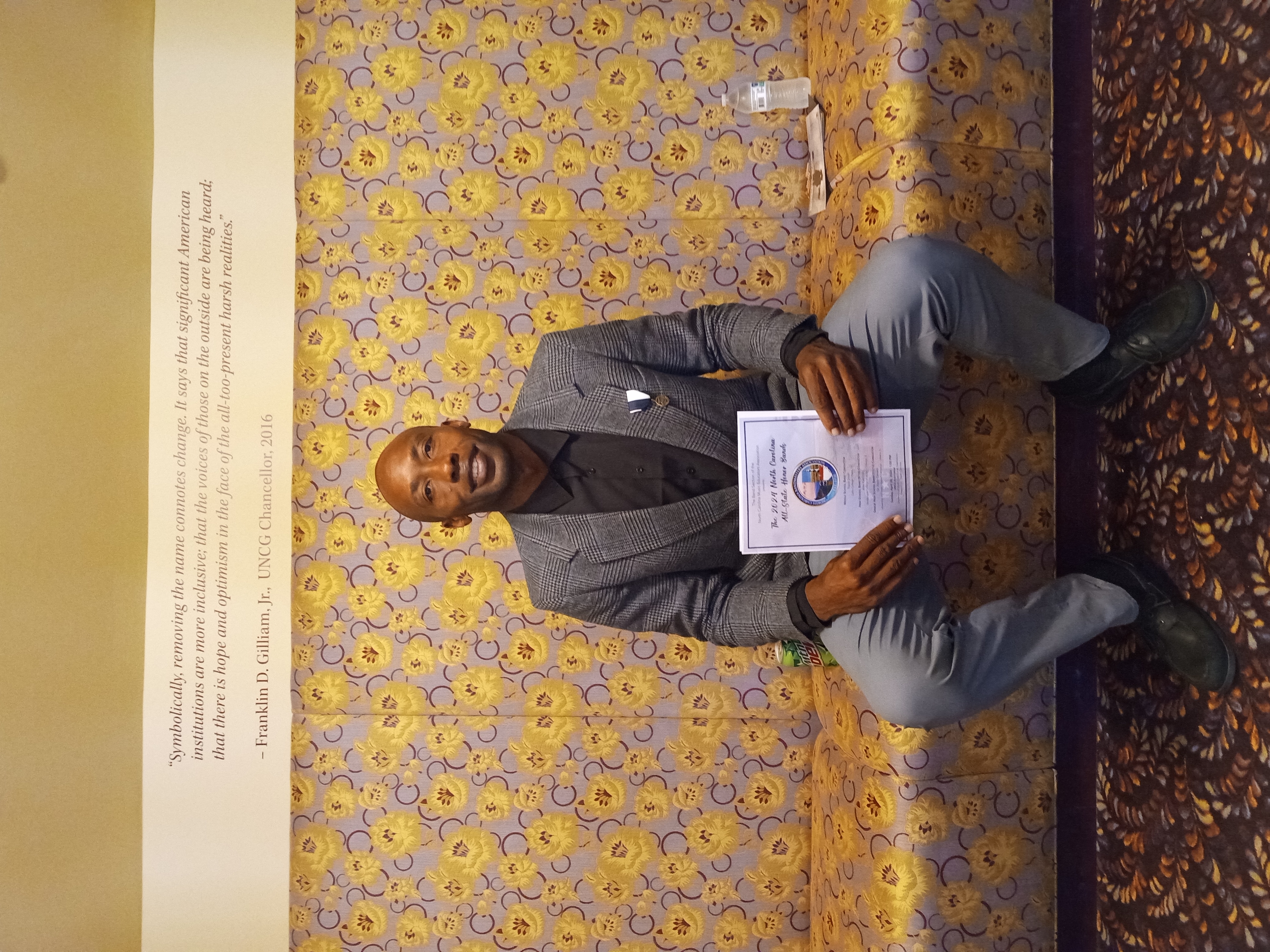 man sitting down holding an award