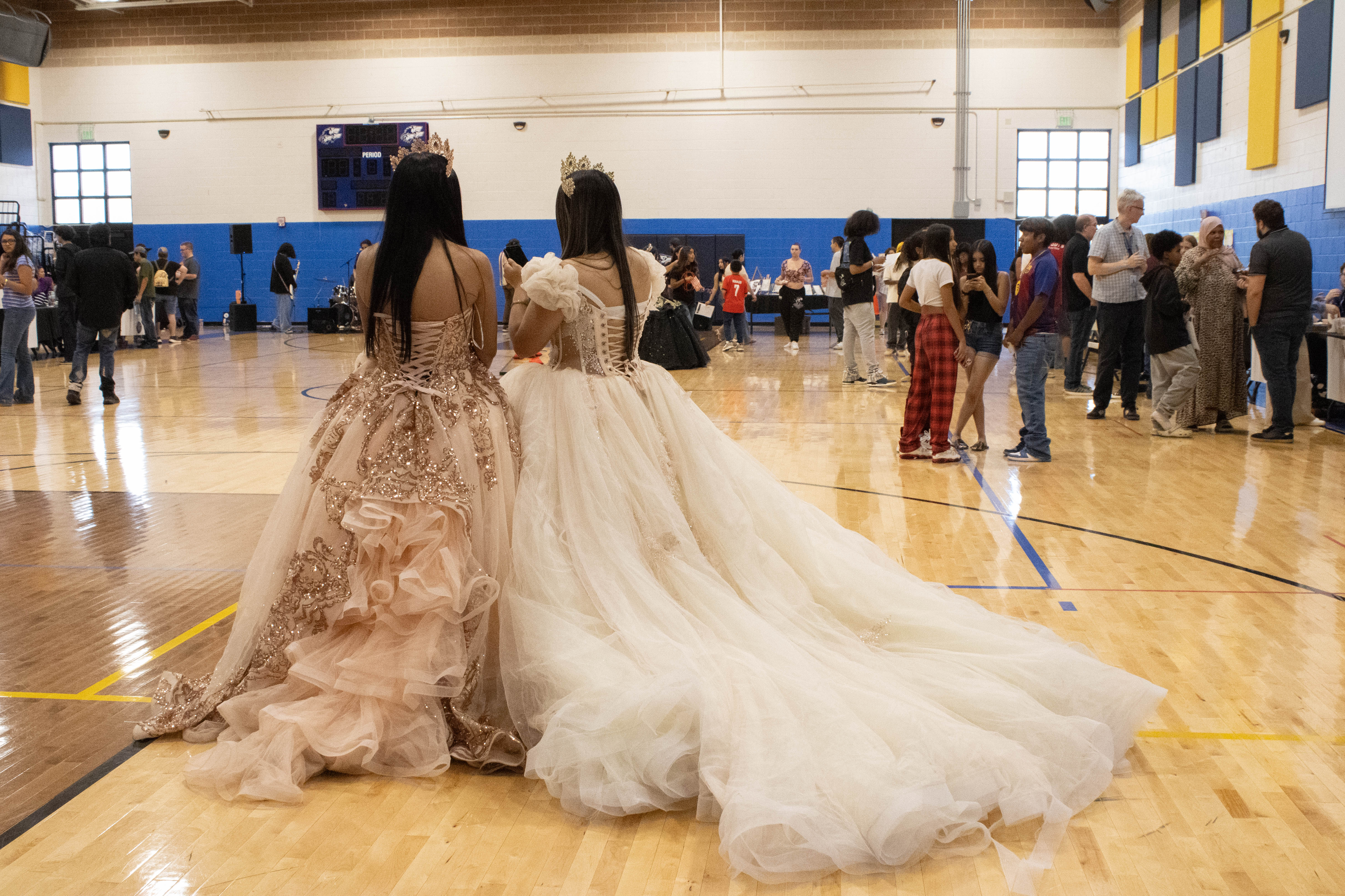 Two NEC students stand in their quinceañera dresses in the gym during back to school night