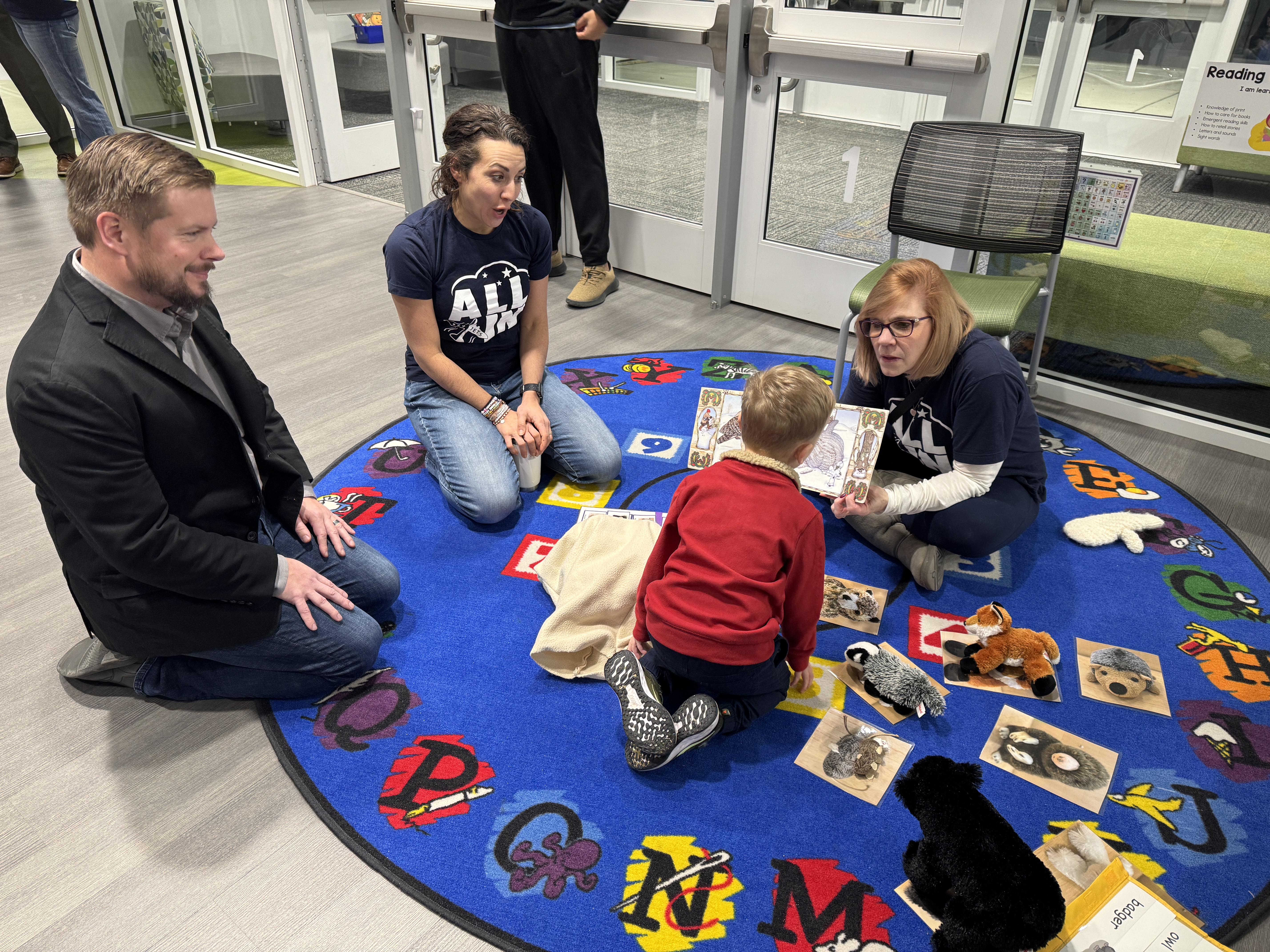 adults and children reading a book
