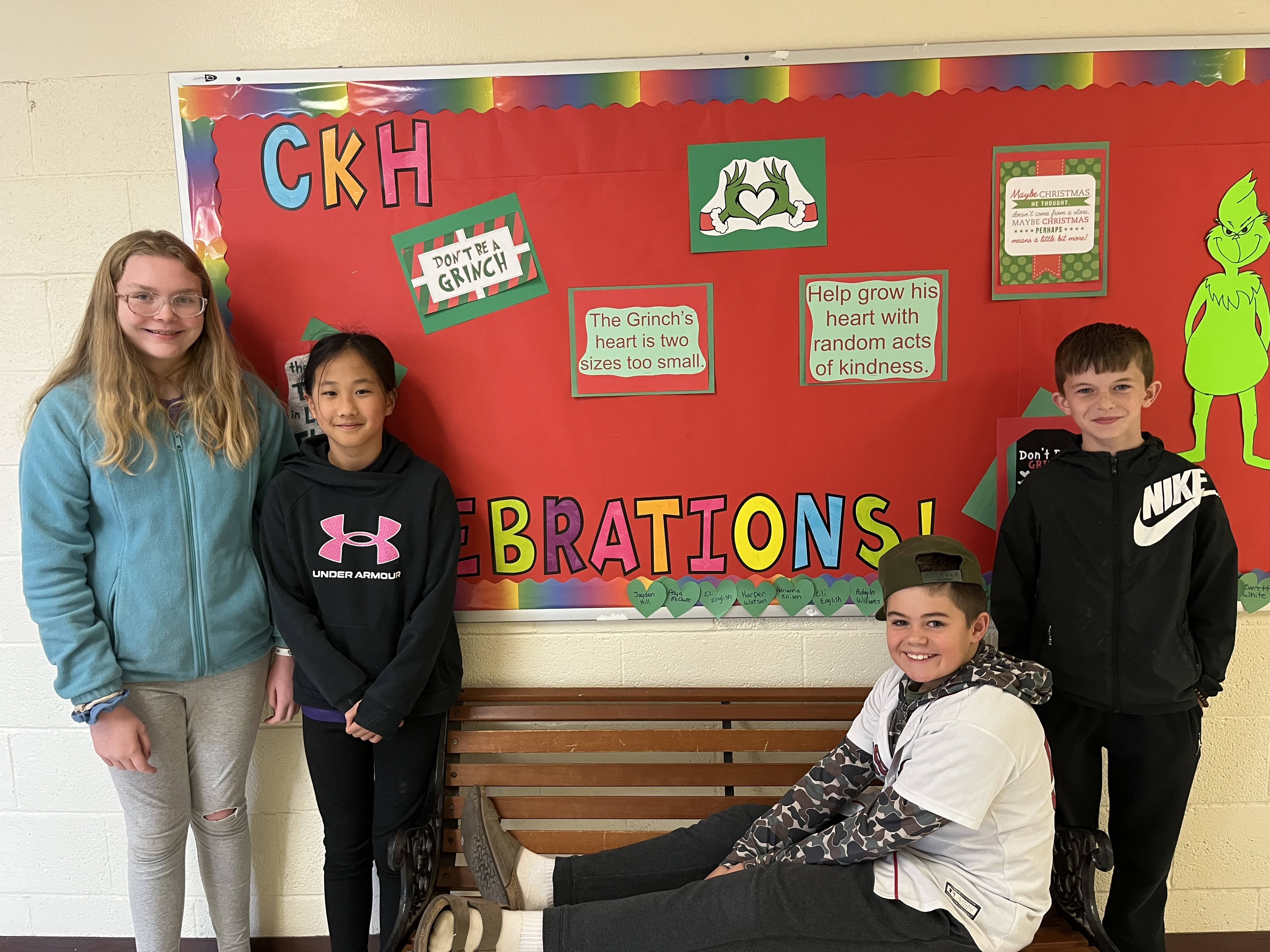 5th graders smiling for the camera in front of a red bulletin board