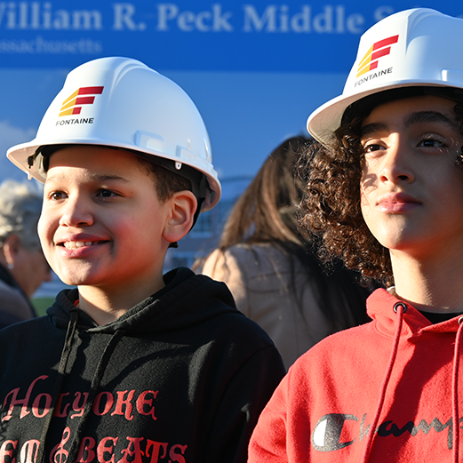 Two boys wearing construction hard hats at groundbreaking