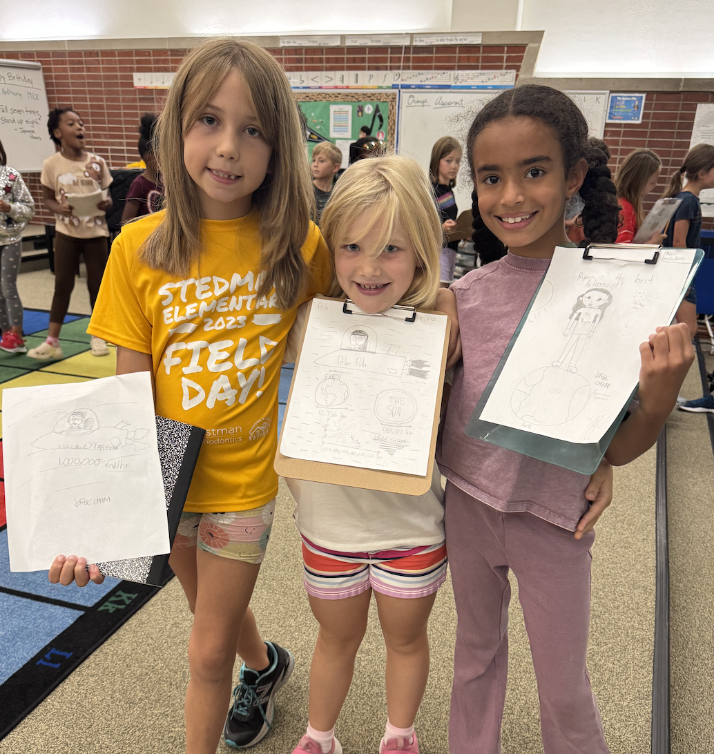 three students displaying their drawing