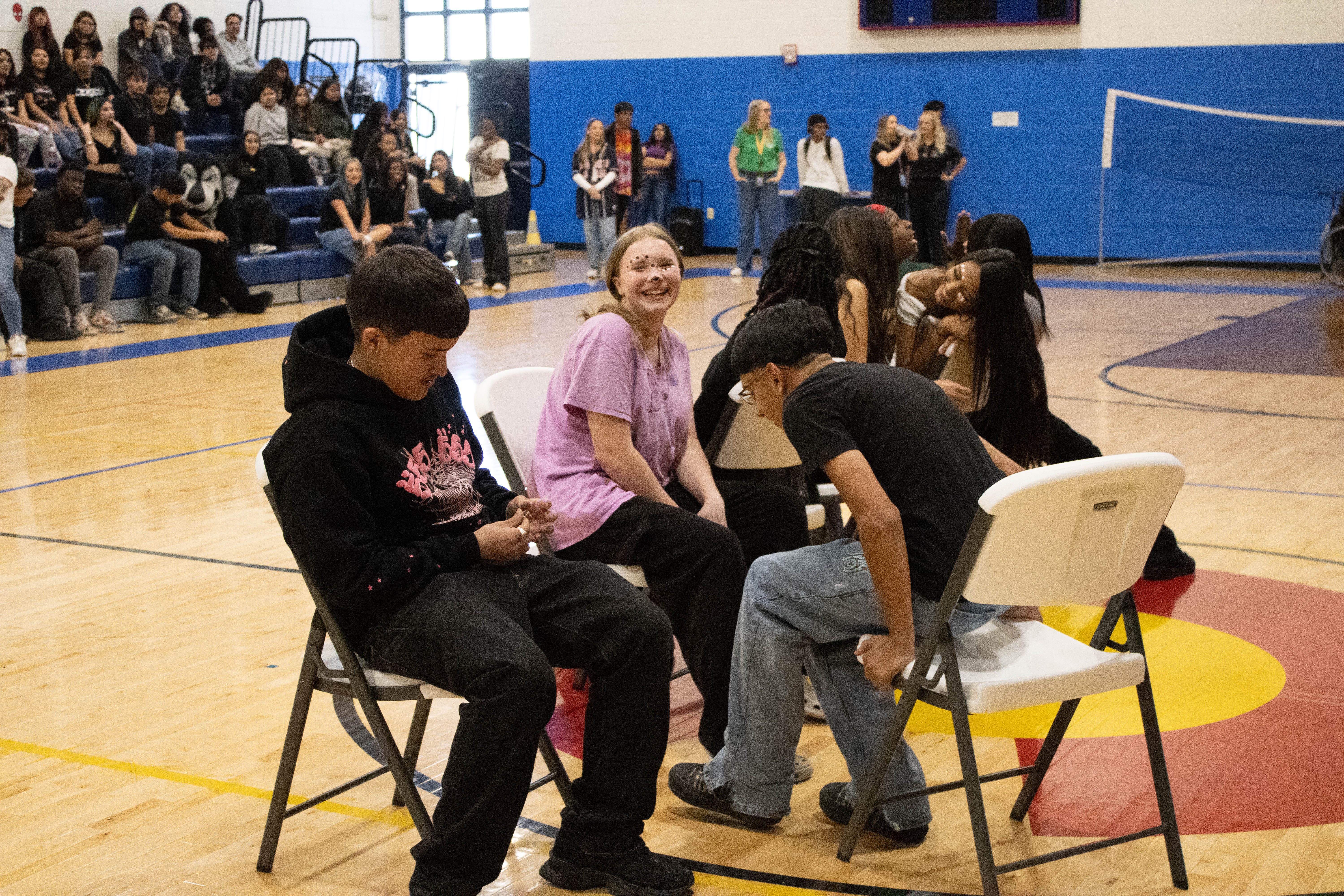 NEC students sitting in chairs laughing as they play musical chairs in the gym