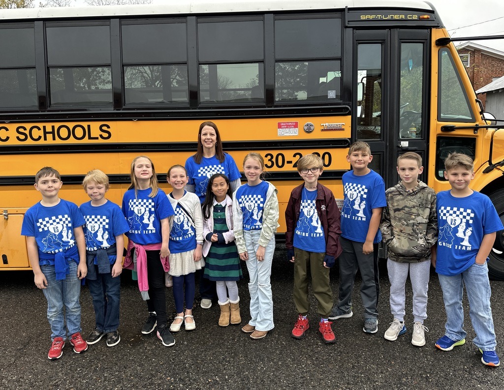 students and Mrs. Cotton smiling in front of the school bus 