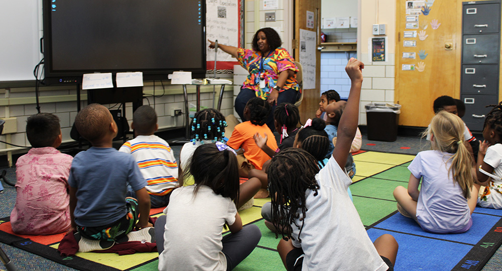 Students on the rug facing their teacher