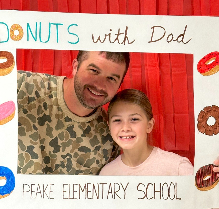 child and dad smiling in a picture frame that says "donuts with Dads"