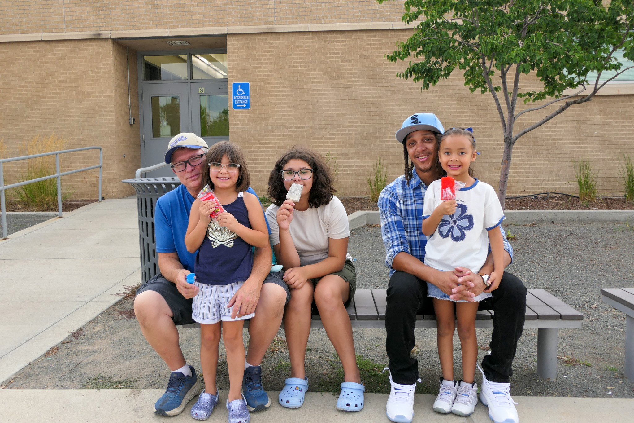 A group of Swansea students and their caregivers pose for a photo while eating ice cream.