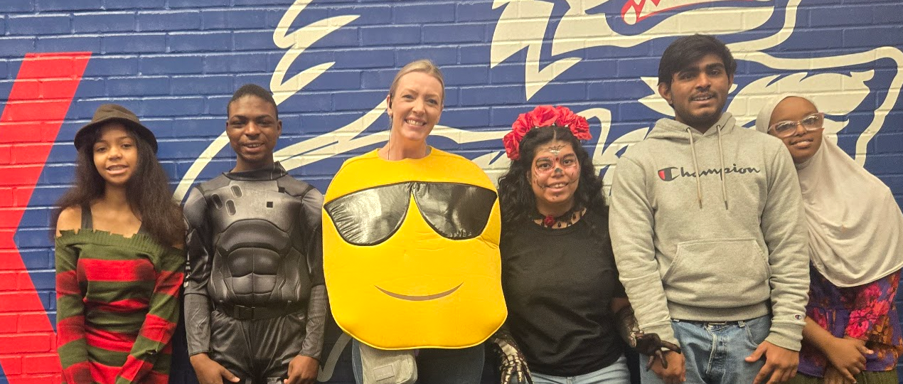 5 students smiling with the principal, who wears an emoji outfit