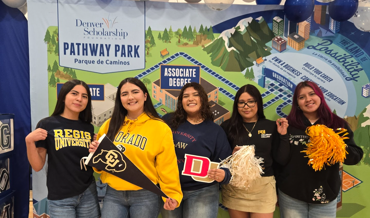 5 students smiling and wearing college gear and holding college memorabilia 