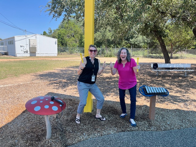 Picture of two staff members with new playground equipment