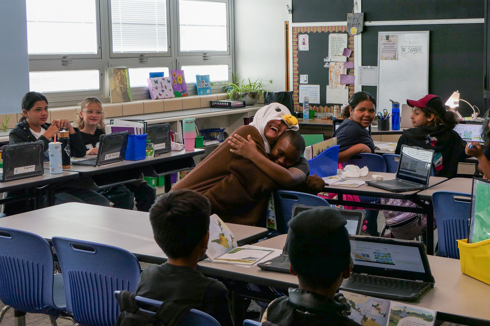A fifth grade student hugs Ellie the Eagle during an attendance celebration. 