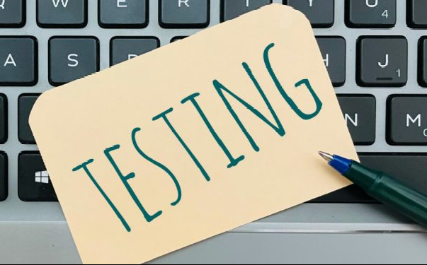 Keyboard and notecard with testing written on it, pen 