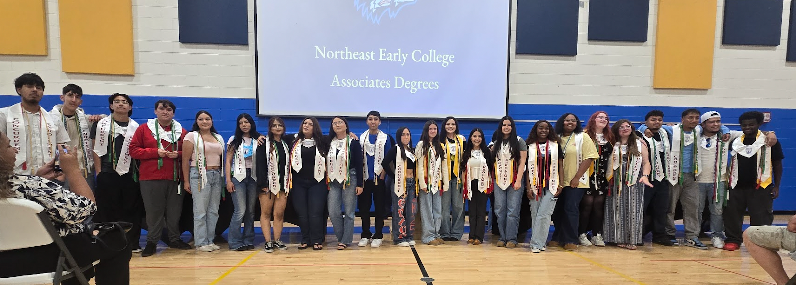 Students wearing stoles under a sign that says "Northeast Early College Associates Degrees"