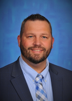 a man in a suit posing in front of a blue background