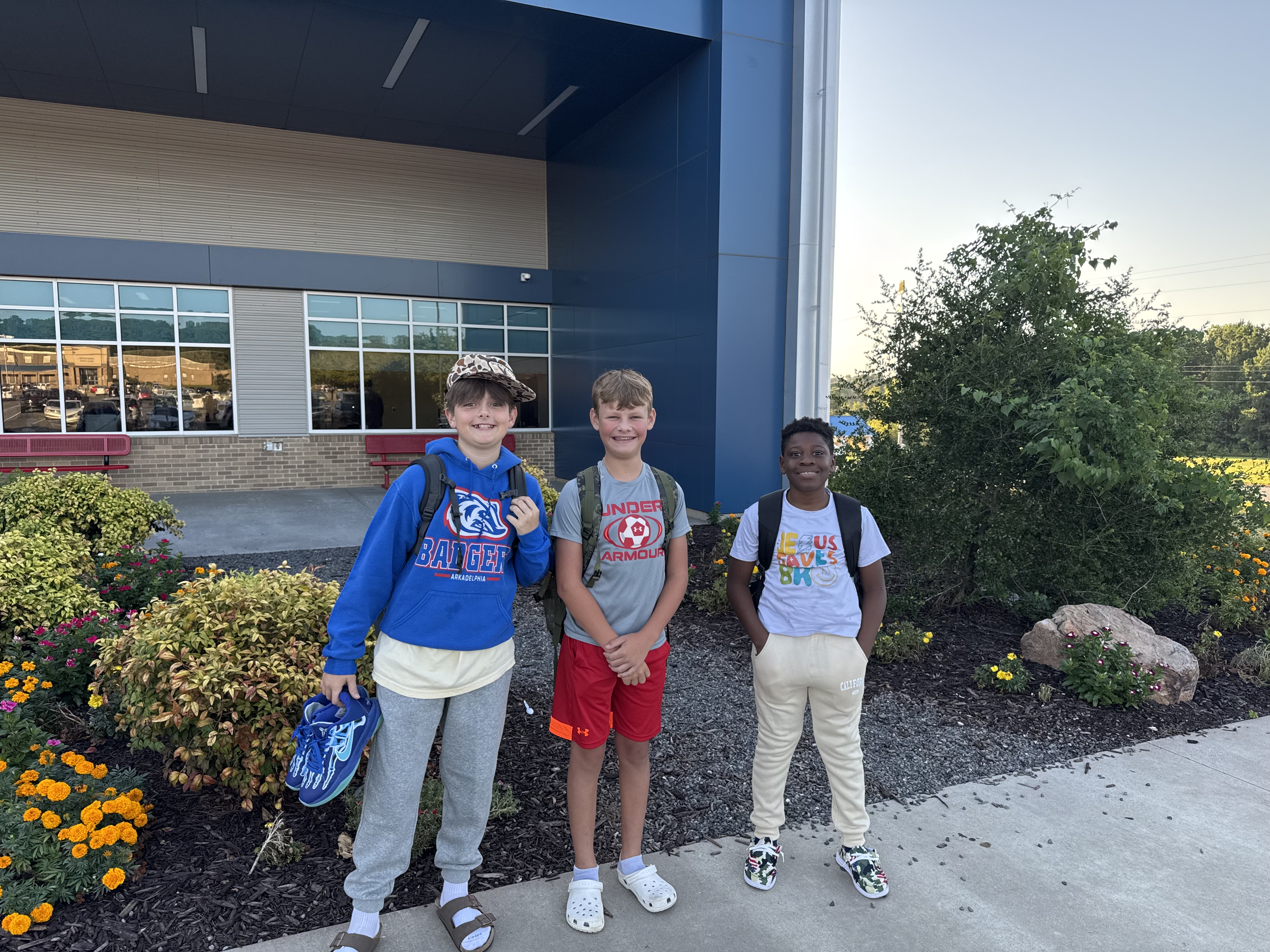 three boys smiling outside the school