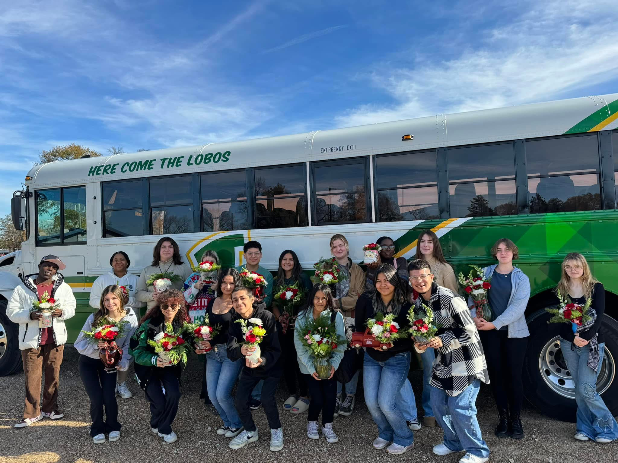 Lobo FFA floral students standing in front of a Longview ISD bus.