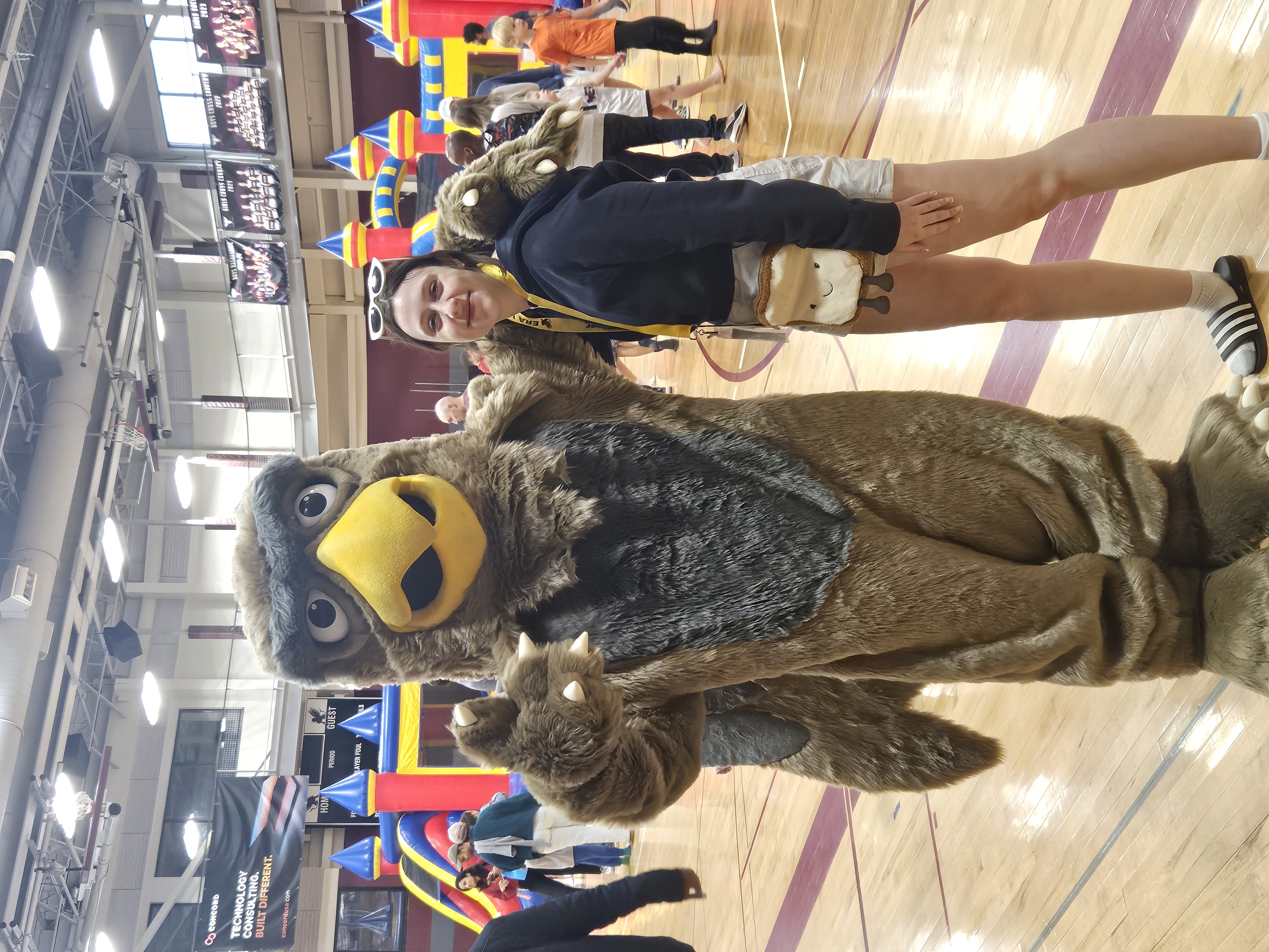 Gus the Gryphon in front of bounce houses