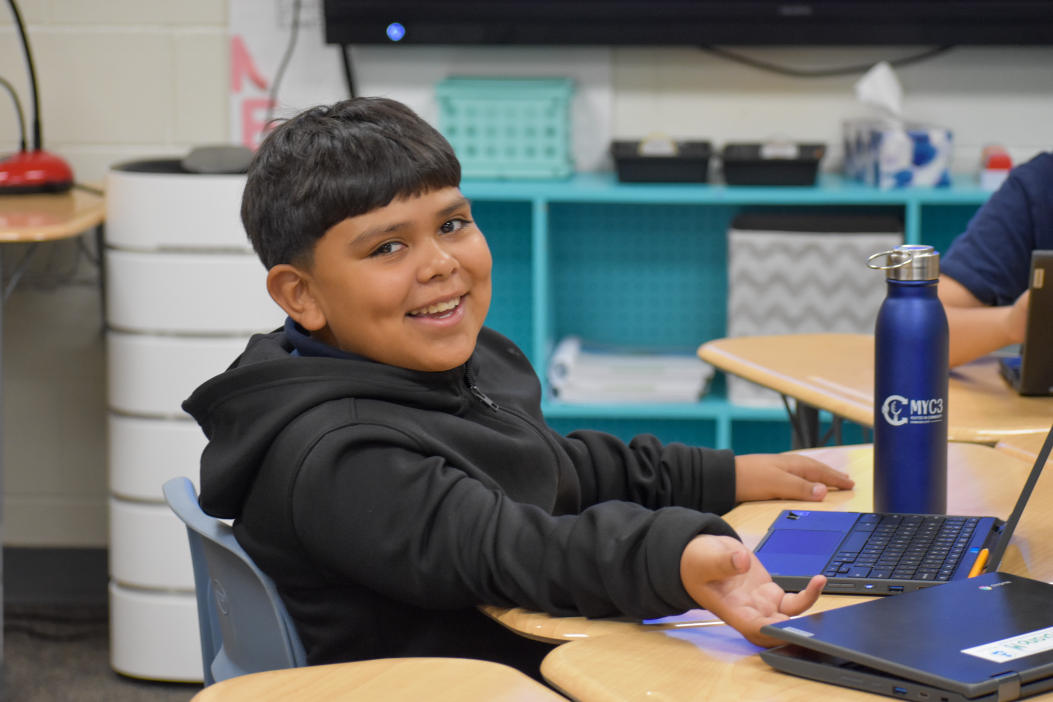 A student smiles while working on his laptop.