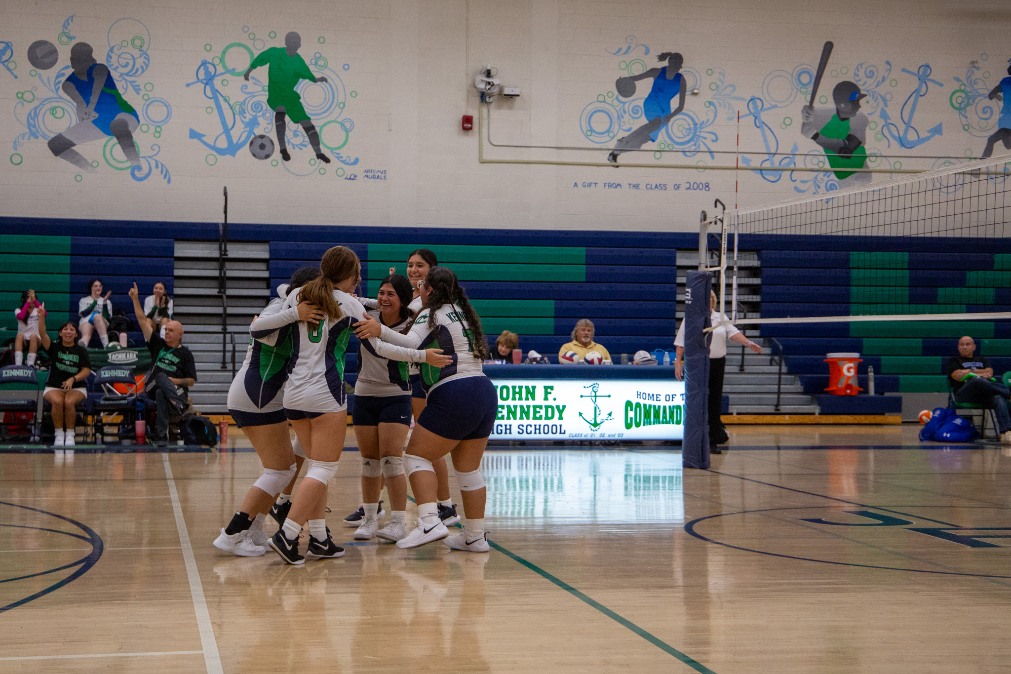 The JV volleyball team huddles together after scoring a point 