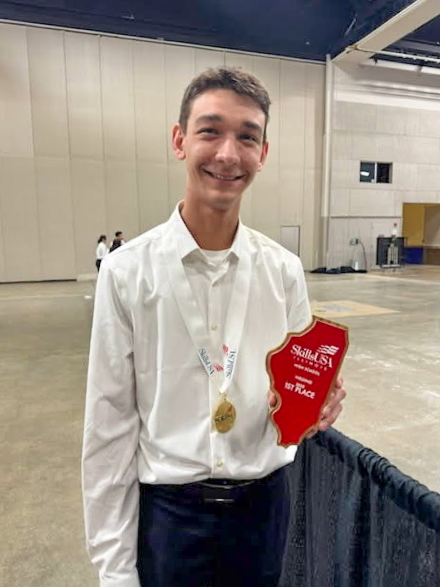 student standing holding plaque and wearing medal
